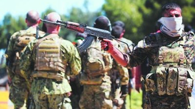 Armed men from the People's Protection Force are on alert at the air raid site.